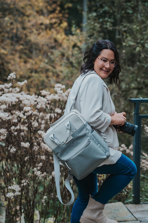 Yasemin Müller mit Kamera und Fototasche im Grünen – Familienfotografin zwischen Baden-Baden und Offenburg.